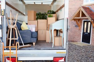 The back of a moving truck, filled with cardboard boxes and furniture