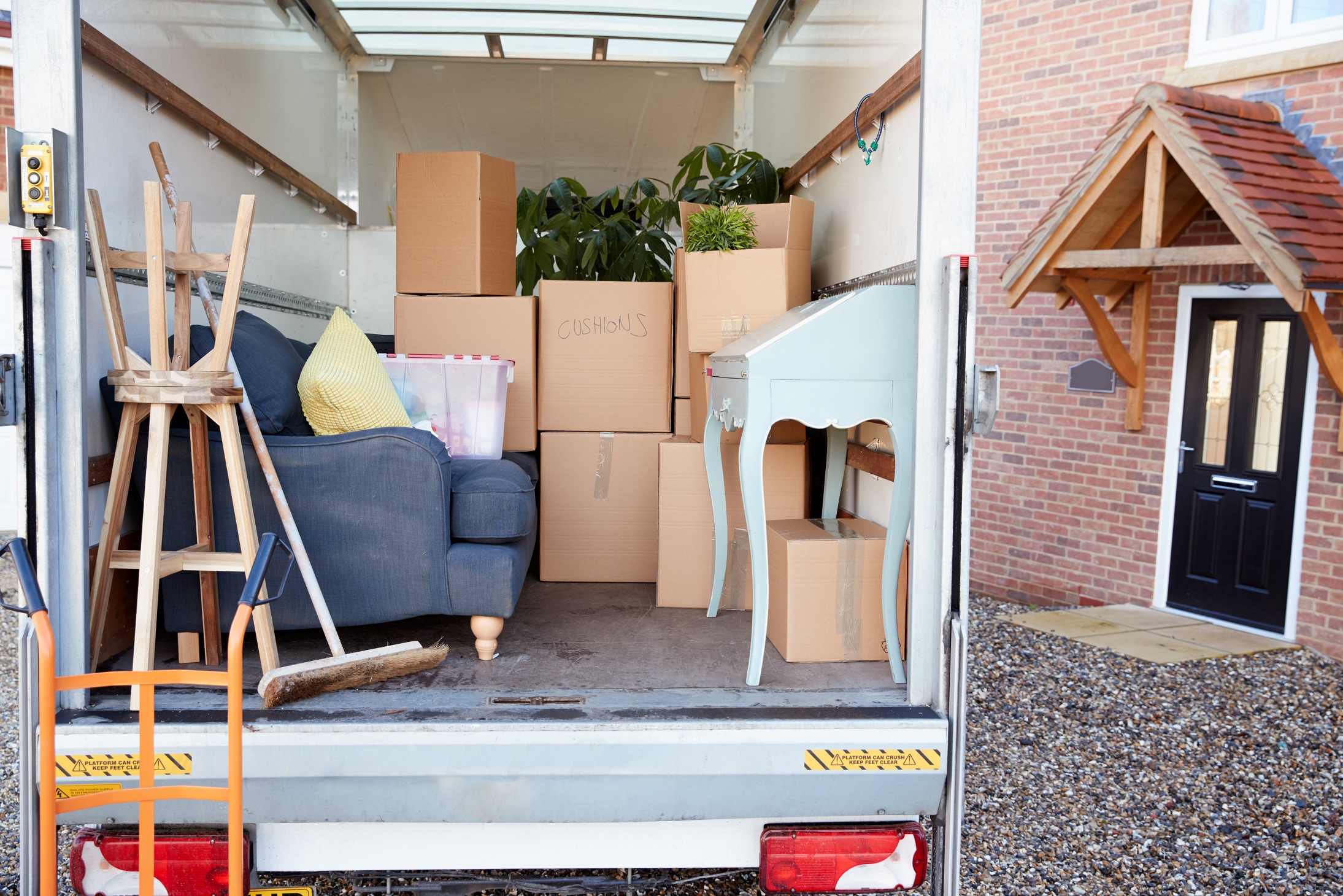 The back of a moving truck, filled with cardboard boxes and furniture